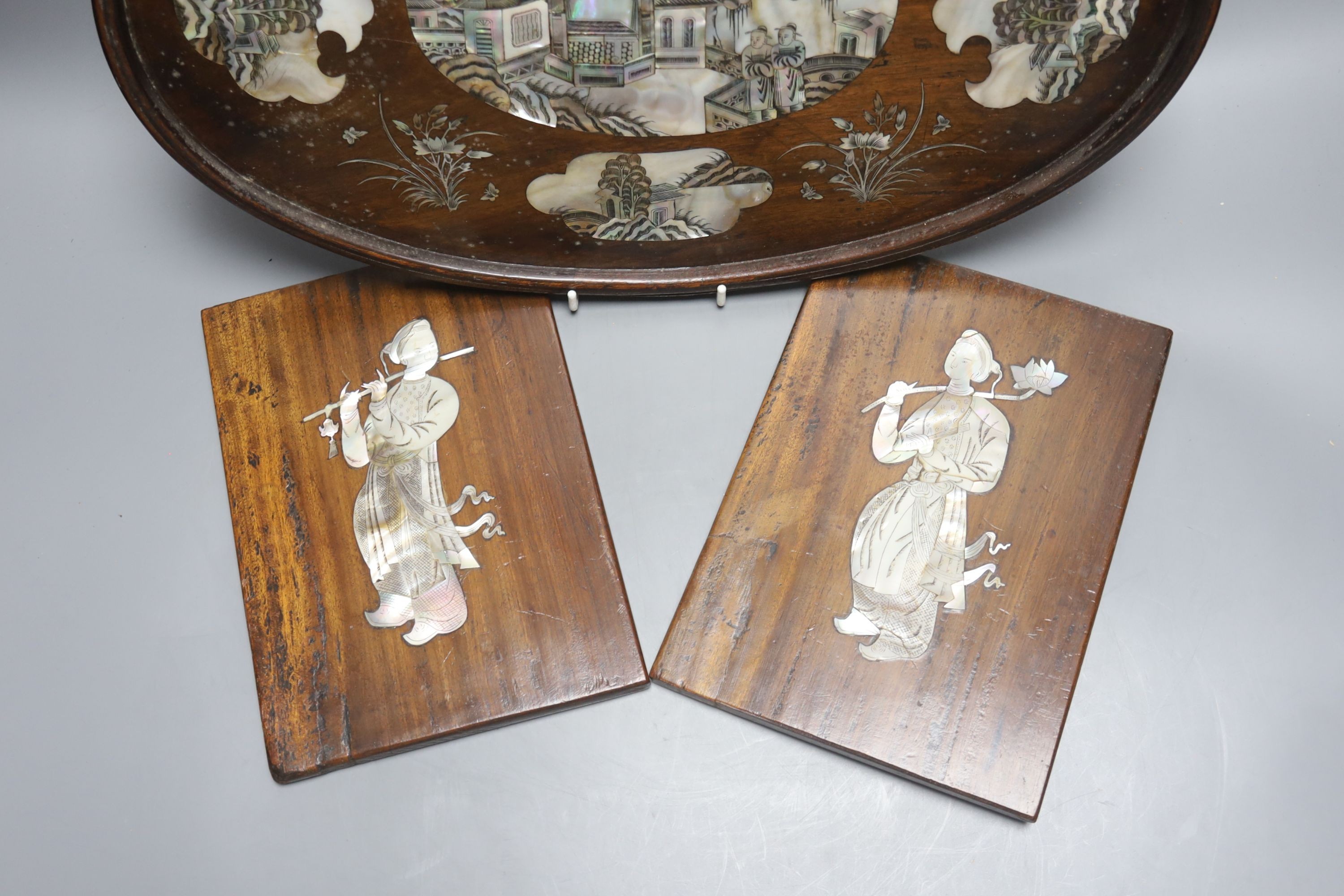 A Chinese hardwood and mother of pearl inlaid oval tray, 43cm and a similar pair of panels decorated with figures